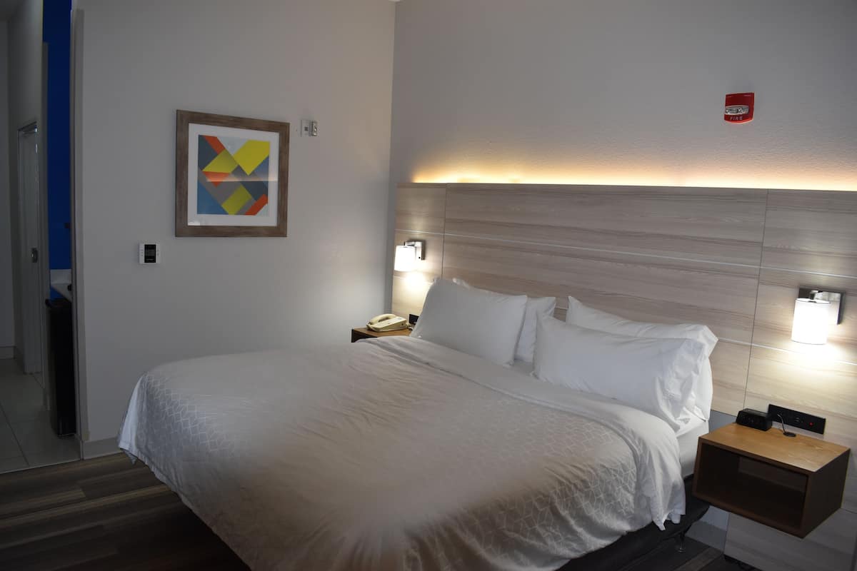 A hotel room with a large bed, bedside lamps, a nightstand, and a framed abstract artwork on the wall.