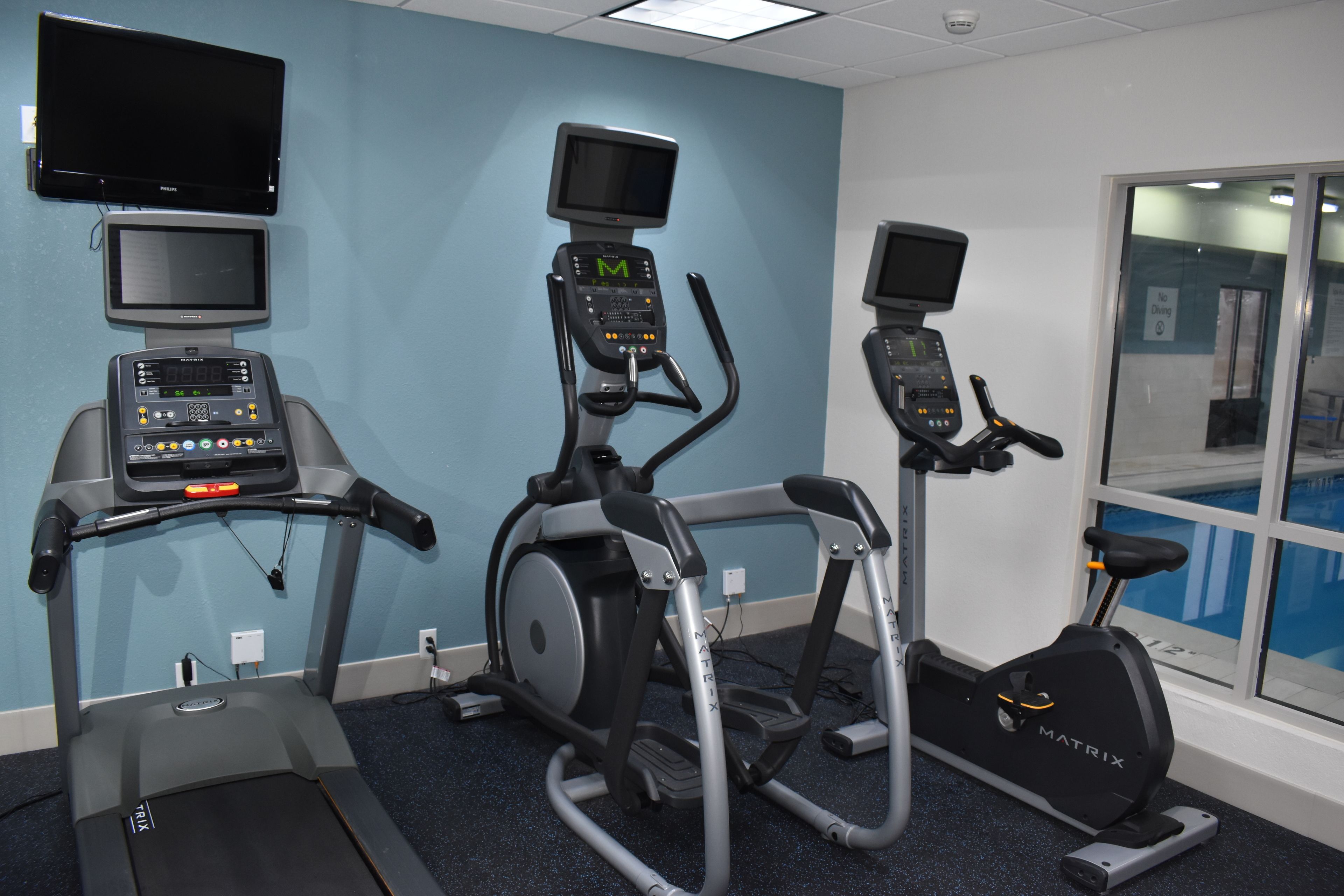 Een fitnessruimte met loopbanden, hometrainers en een roeimachine, voorzien van digitale displays en bedieningspanelen.