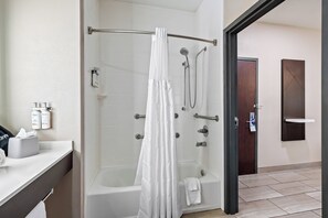 A modern bathroom with a walk-in shower, a bathtub, and a vanity with toiletries.