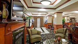 A hotel lobby with a central seating area, a reception desk, and a large mirror. - Holiday Inn Express Ada by IHG (Ada)