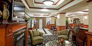 Un hall de hotel con una zona de estar central, un mostrador de recepción y un espejo grande.