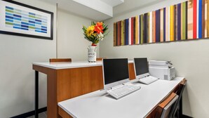 A modern office space with a wooden reception desk, two desktop computers, and a vase with flowers. - Holiday Inn Express Ada by IHG (Ada)