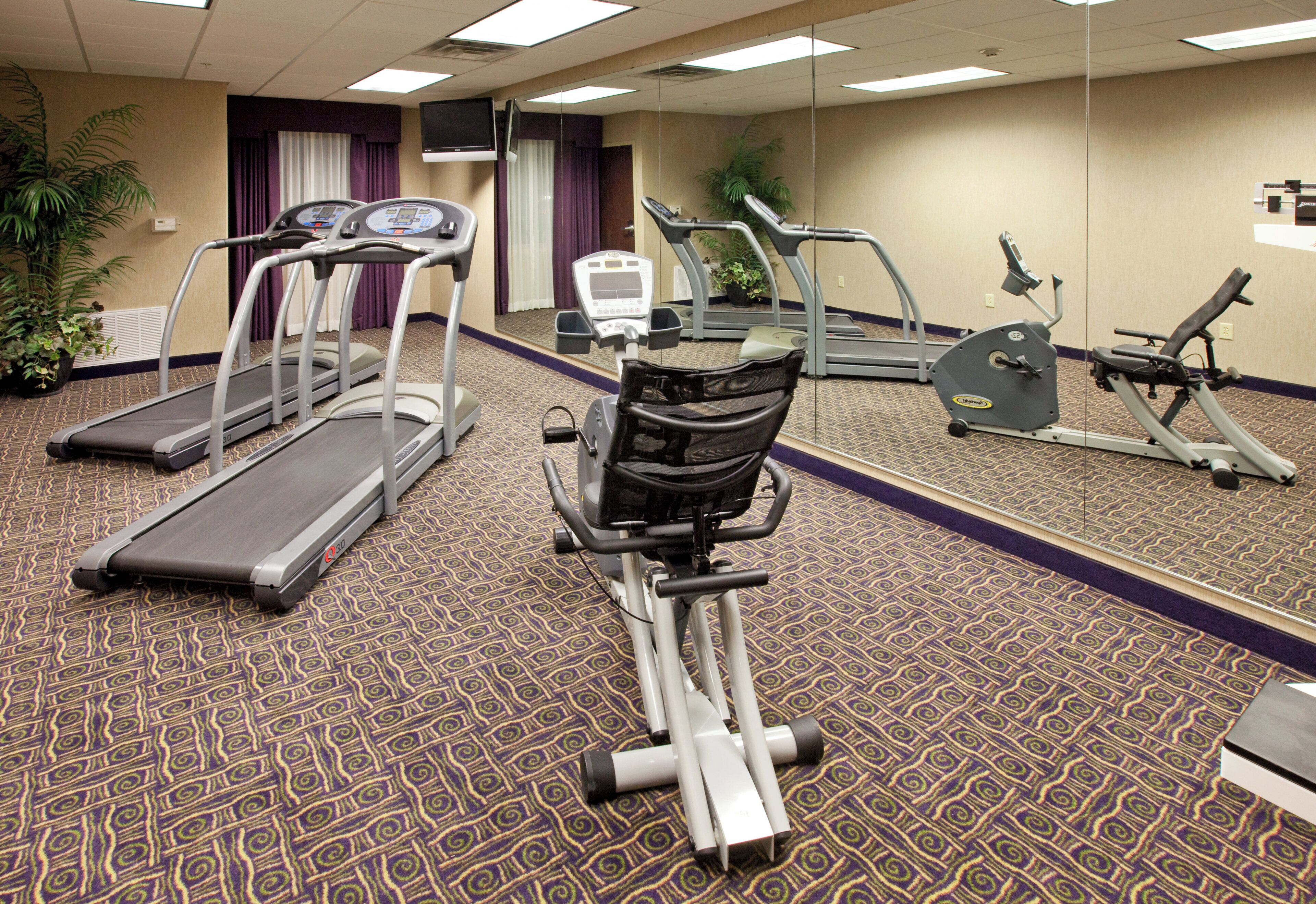 Un centre de remise en forme équipé de tapis de course, d’un vélo elliptique et d’un vélo d’appartement.