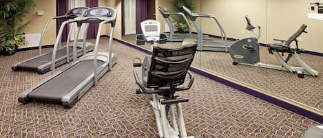 Un centre de remise en forme équipé de tapis de course, d’un vélo elliptique et d’un vélo d’appartement.