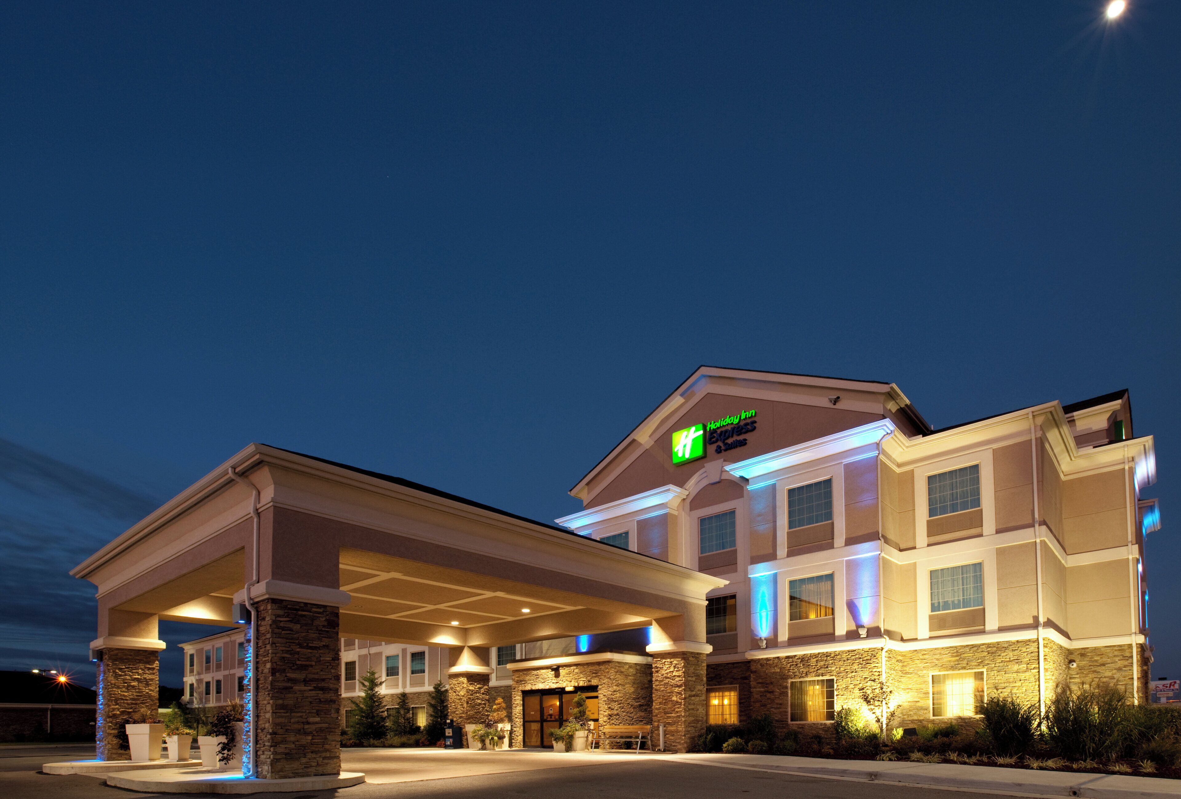 Un hôtel Holiday Inn Express doté d’une entrée couverte, d’une façade en pierre et d’une enseigne lumineuse.
