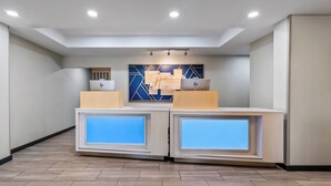A reception area with two reception desks, a blue wall with geometric patterns, and a ceiling with recessed lighting. - Holiday Inn Express Ada by IHG (Ada)