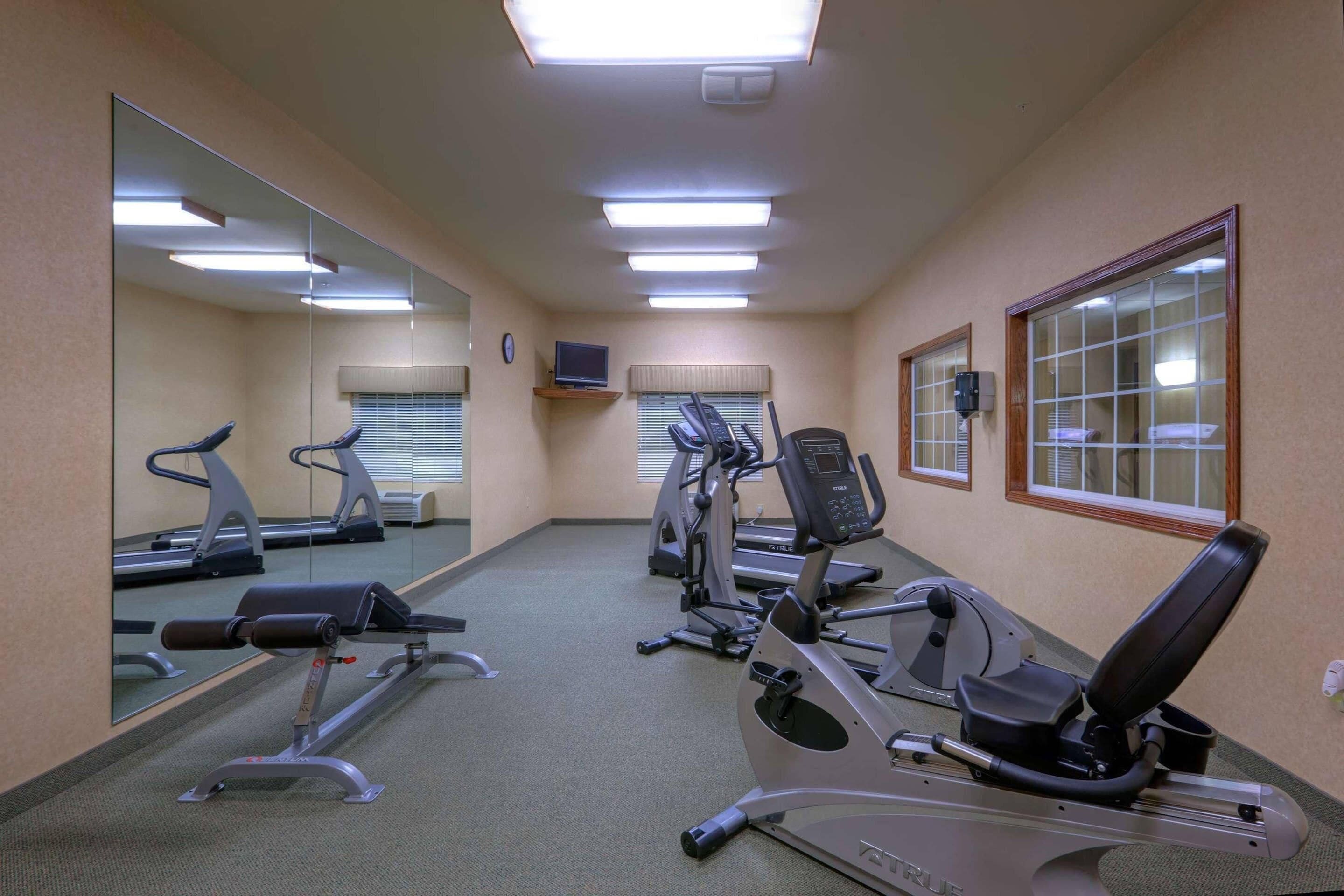 Un gimnasio con equipo de ejercicio, espejos y una televisión.