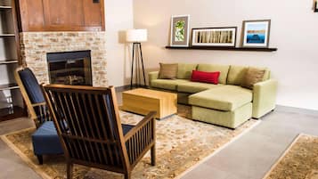 Un salon avec une cheminée, un canapé, un fauteuil, une lampe sur pied et une table basse.