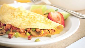 A breakfast plate with an omelette, vegetables, and a glass of orange juice.