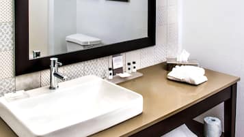 A bathroom with a large sink, a mirror, a towel rack, and a toilet visible in the reflection.