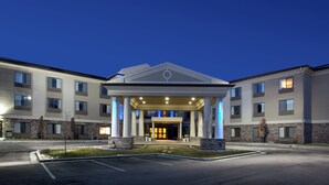 A hotel entrance with a covered walkway, columns, and a parking lot. - Holiday Inn Express Hotel & Stes Salt Lake City-Airport East by IHG (Salt Lake City)