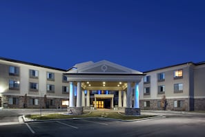 A hotel entrance with a covered walkway, columns, and a parking lot. - Holiday Inn Express Hotel & Stes Salt Lake City-Airport East by IHG (Salt Lake City)