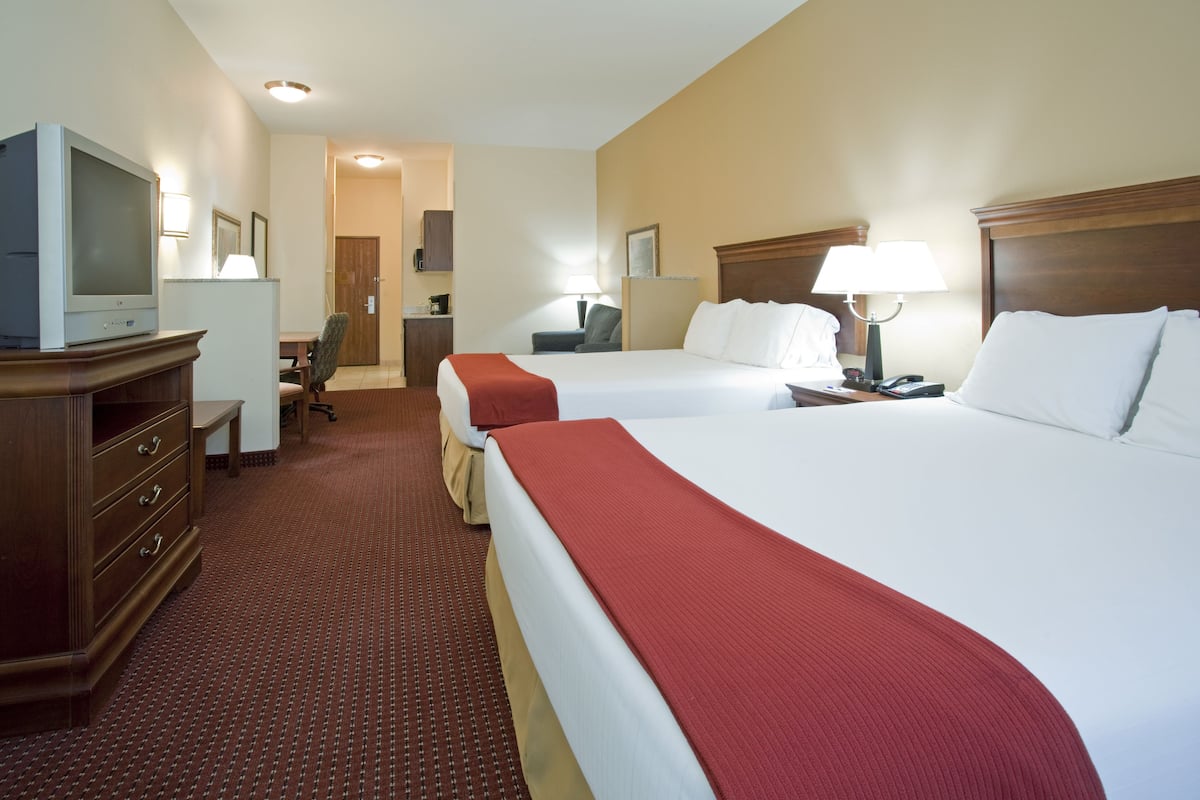 A hotel room with two beds, a TV, a desk, and a chair.