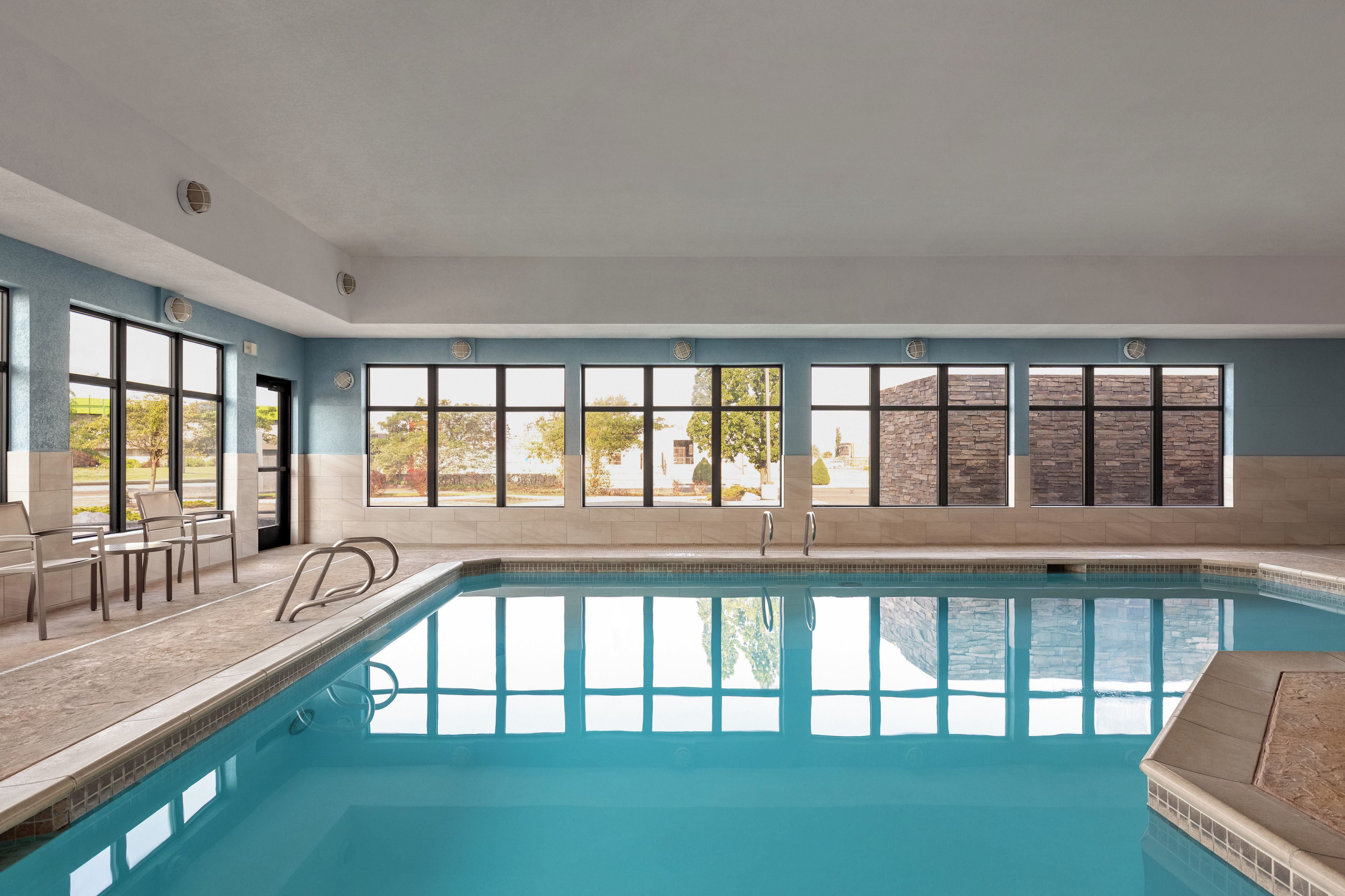 A swimming pool with a clear view of the surrounding area, including a stone wall and trees.