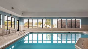 A swimming pool with a clear view of the surrounding area, including a stone wall and trees.