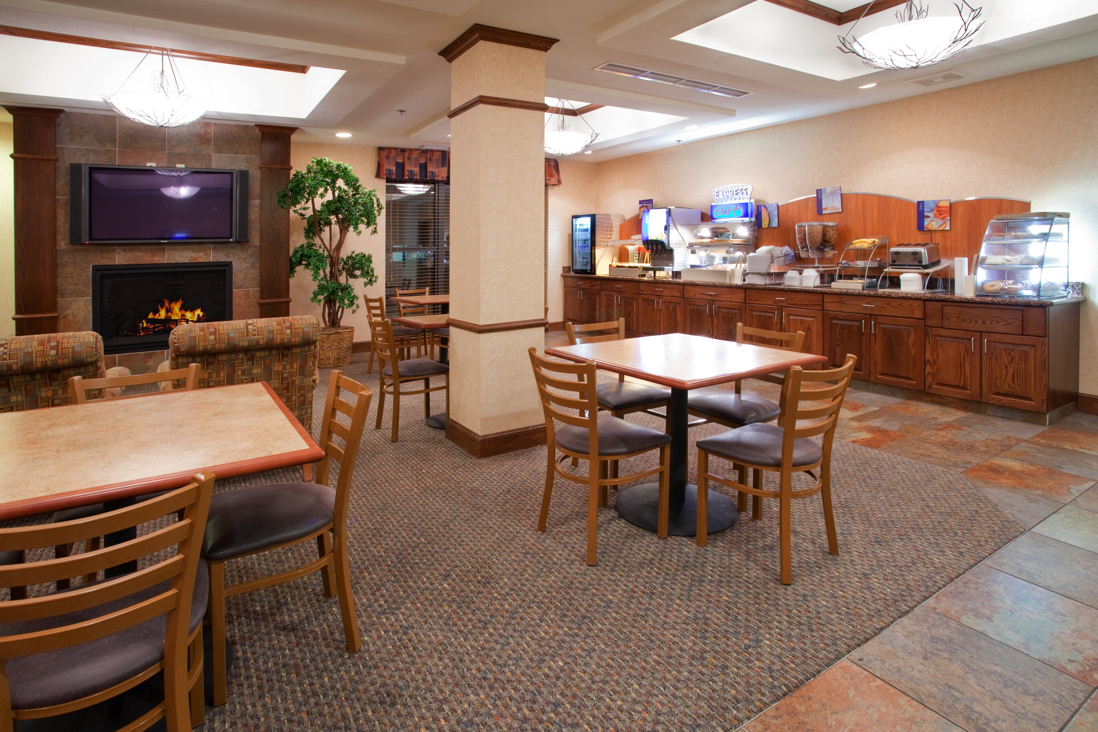 Um hall de hotel com lareira, área de estar e balcão de café da manhã.
