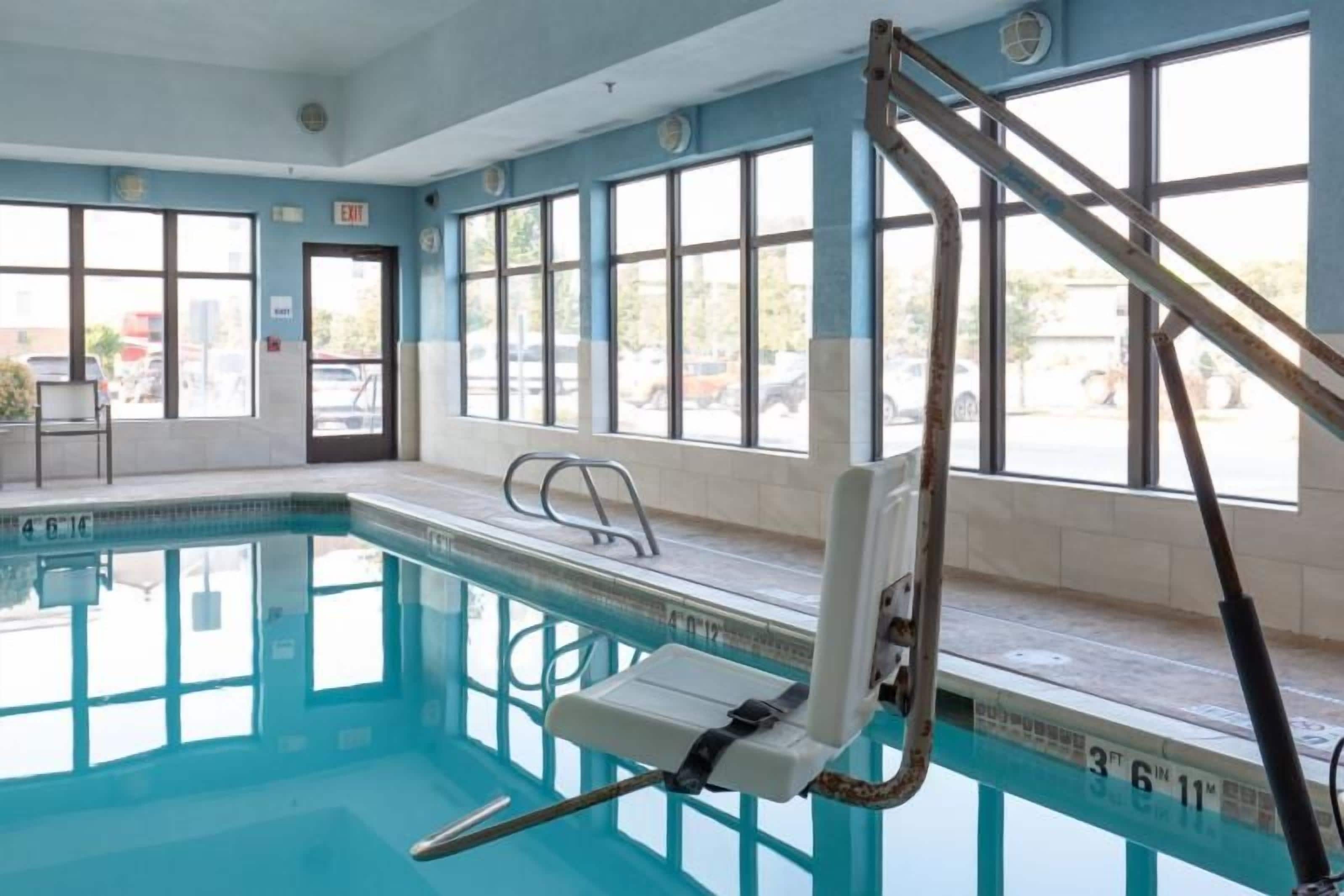 An indoor swimming pool with clear windows, a lifeguard chair, and a pool ladder.