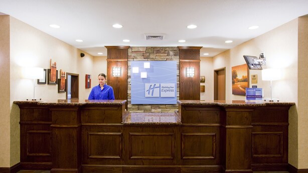 A reception desk with a stone accent wall, wooden paneling, and a Holiday Inn Express sign. - Holiday Inn Express Hotel & Stes Salt Lake City-Airport East by IHG (Salt Lake City)