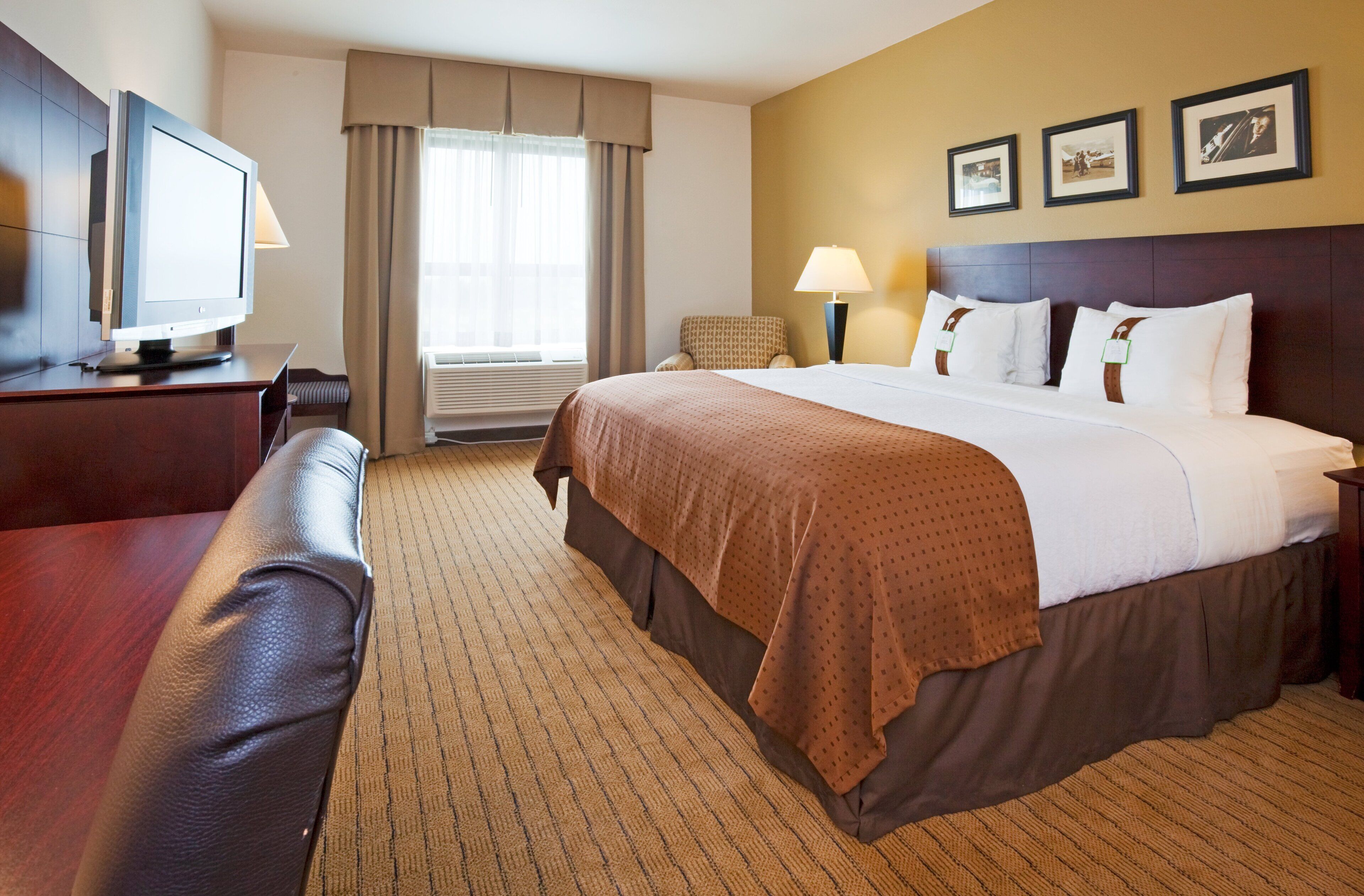 A hotel room with a bed, a desk, a chair, a television, and a window with curtains.