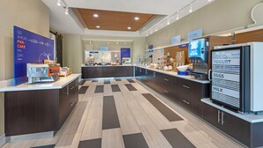 A modern kitchen with a central island, a refrigerator with a yogurt, eggs, and milk display, and a sign indicating a breakfast menu. - Holiday Inn Express Hotel & Suites Fairfield - North by IHG (Fairfield)