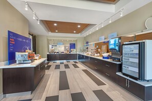 A modern kitchen with a central island, a refrigerator with a yogurt, eggs, and milk display, and a sign indicating a breakfast menu. - Holiday Inn Express Hotel & Suites Fairfield - North by IHG (Fairfield)