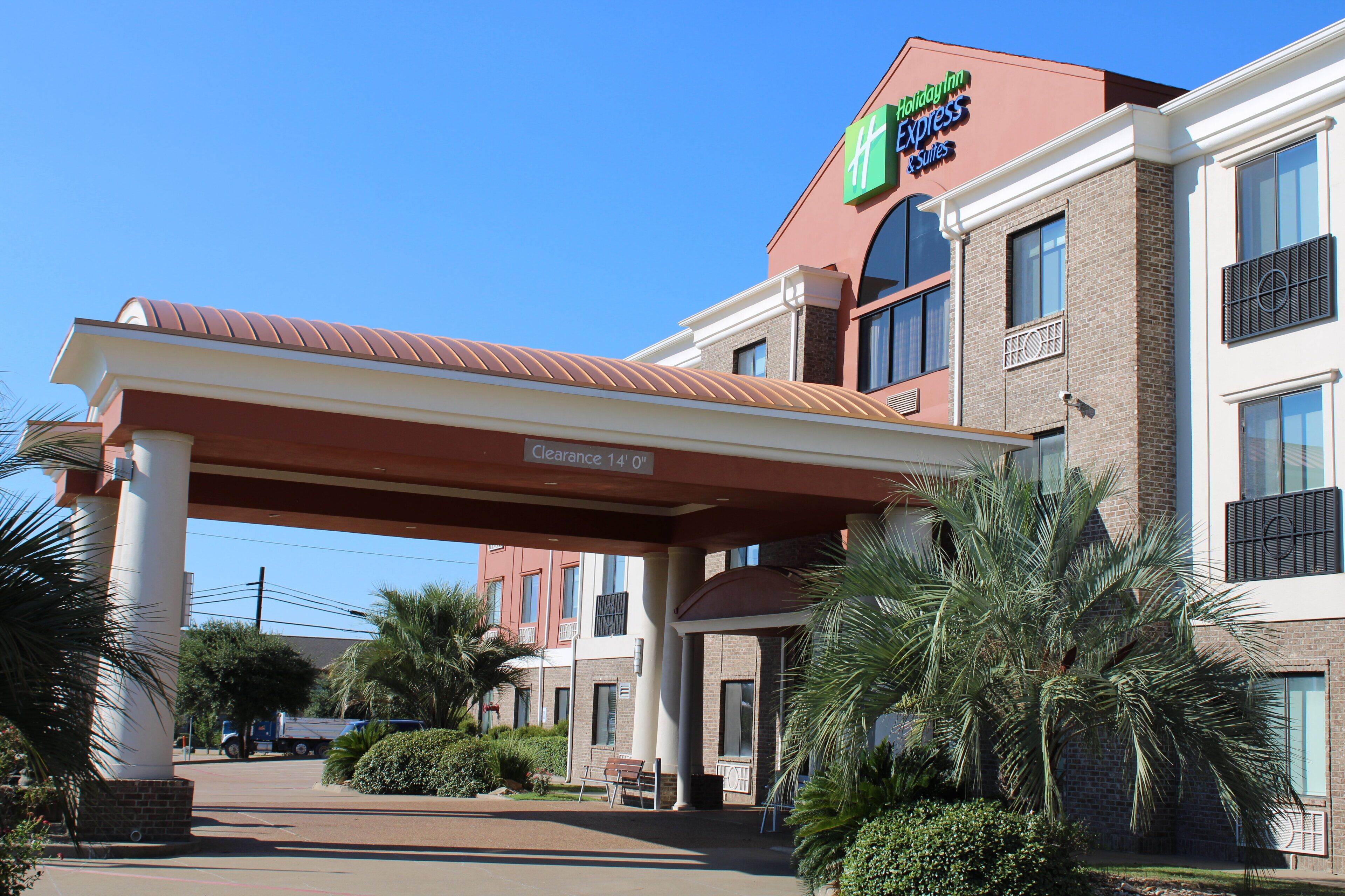 A Holiday Inn Express & Suites with a clear sky, a covered entrance, and a parking lot.