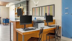 Un moderno spazio ufficio con due scrivanie, ciascuna dotata di computer, tastiera e monitor. Su una scrivania c'è una stampante, e sopra le scrivanie un'ampia opera d'arte astratta con strisce colorate.
