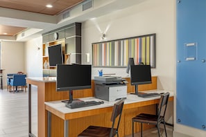 A modern office space with two desks, each equipped with a computer, keyboard, and monitor. There is a printer on one desk, and a large, colorful striped wall art piece above the desks. - Holiday Inn Express Hotel & Suites Fairfield - North by IHG (Fairfield)