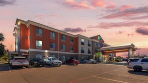 A multi-story hotel with a parking lot, featuring a prominent sign and a well-lit entrance. - Holiday Inn Express Hotel & Suites Fairfield - North by IHG (Fairfield)