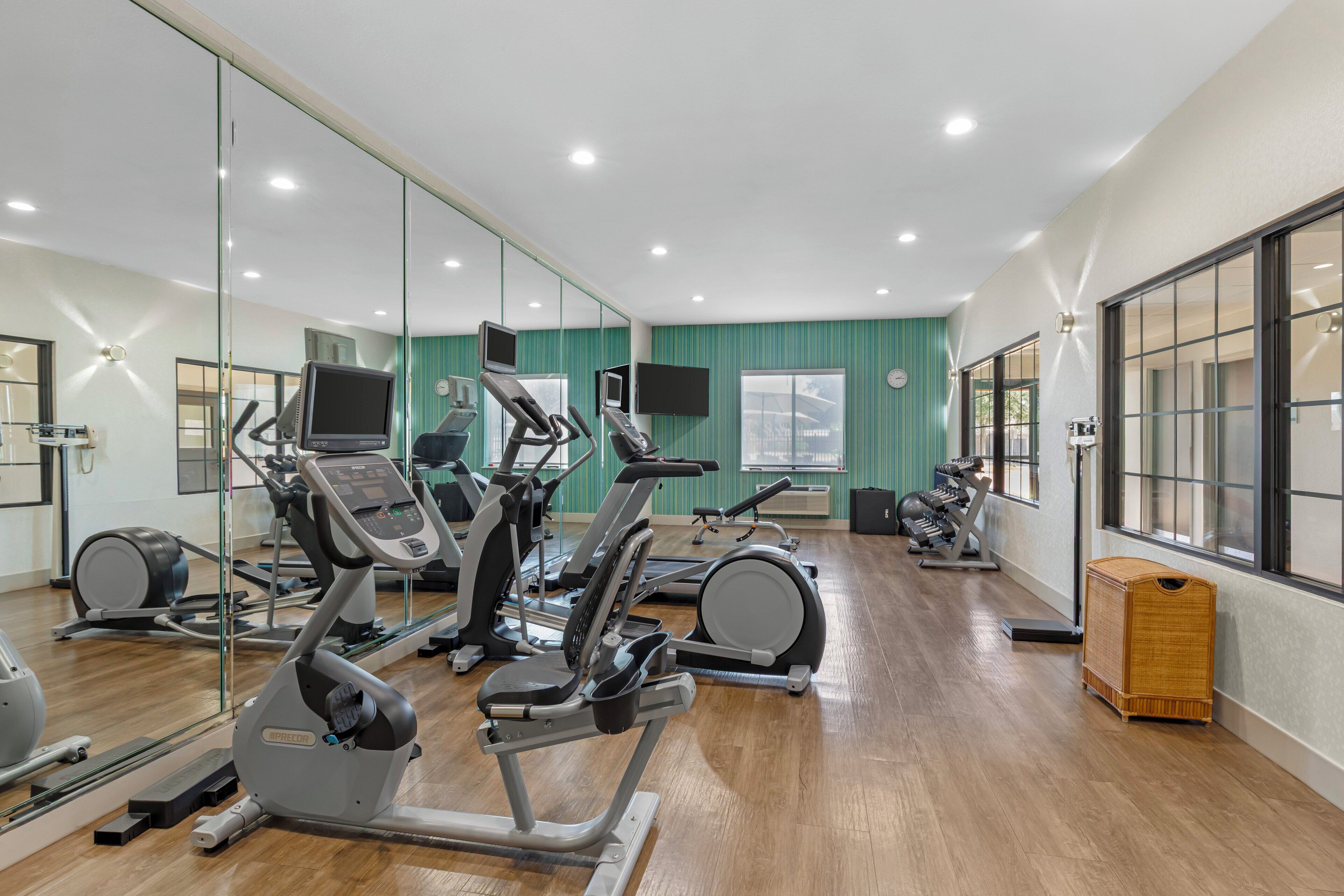 A gym with exercise equipment, a large mirror, and a television.