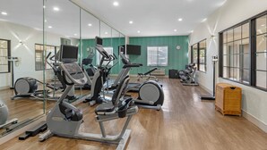 Una palestra con attrezzi per esercizi, un ampio specchio e un televisore.