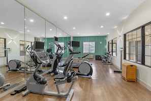 A gym with exercise equipment, a large mirror, and a television. - Holiday Inn Express Hotel & Suites Fairfield - North by IHG (Fairfield)