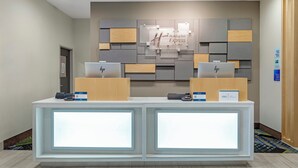 A reception desk with two computer stations, a wall-mounted sign for Holiday Inn Express & Suites, and a door to the left. - Holiday Inn Express Hotel & Suites Fairfield - North by IHG (Fairfield)