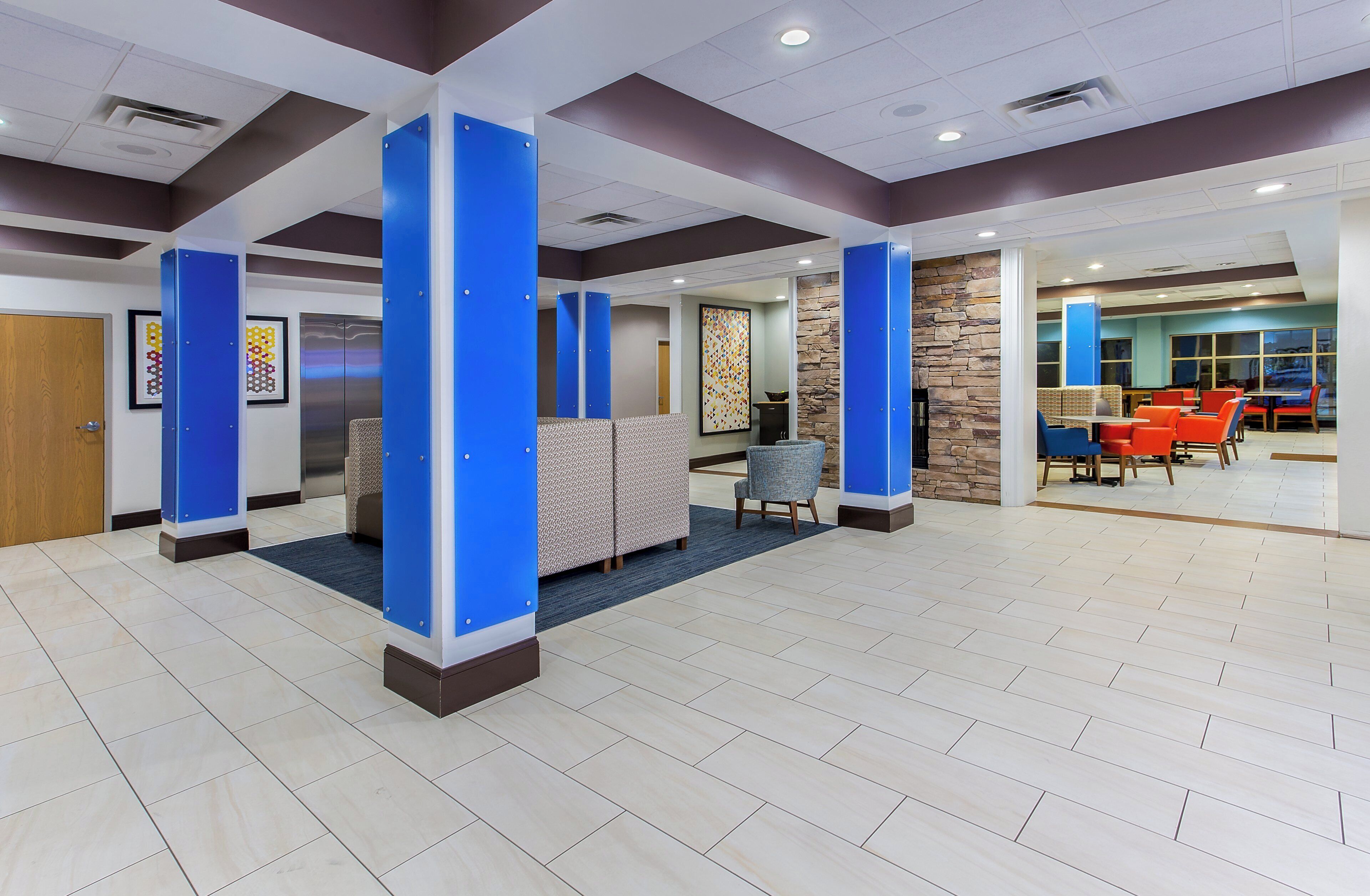A modern lobby with a reception desk, seating area, and a dining section.