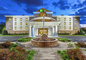 A hotel with a central entrance, a flagpole, and a landscaped area with a circular stone feature. - Holiday Inn Express & Suites Morristown by IHG (Morristown)