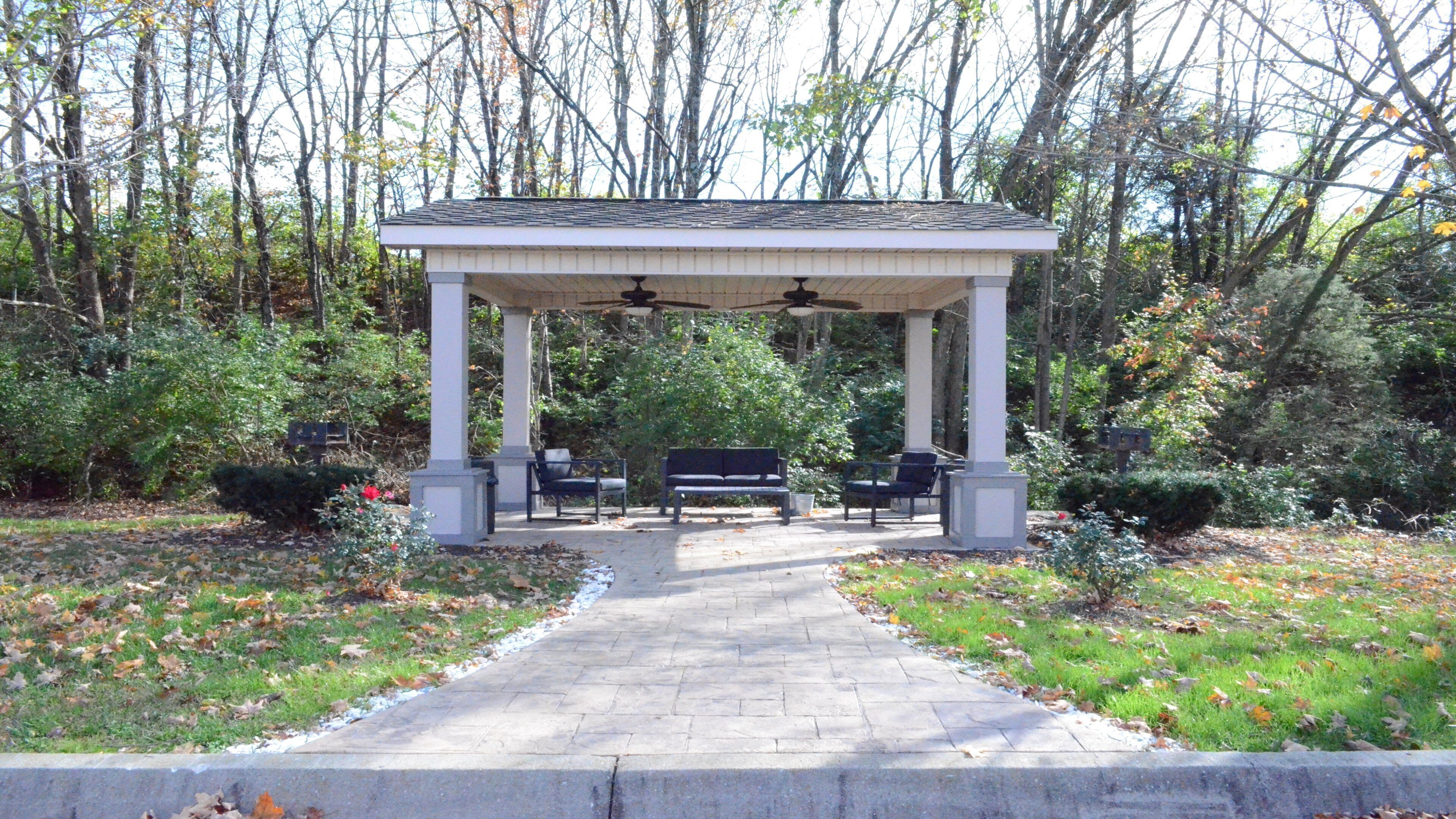 A covered pavilion with a central seating area and a pathway leading to it.