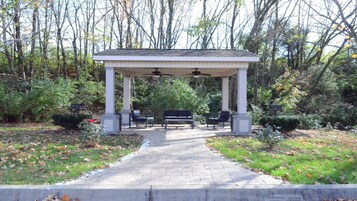 A covered pavilion with a central seating area and a pathway leading to it.