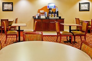 A hotel dining area with a central counter, multiple tables, and chairs. - Holiday Inn Express & Suites Dickson by IHG (Dickson)