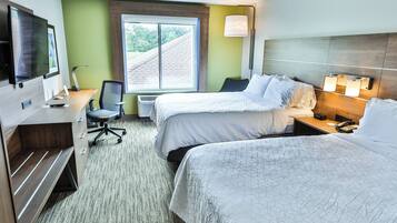 A hotel room with two beds, a desk with a computer, a TV, and a window with a view of the roof.