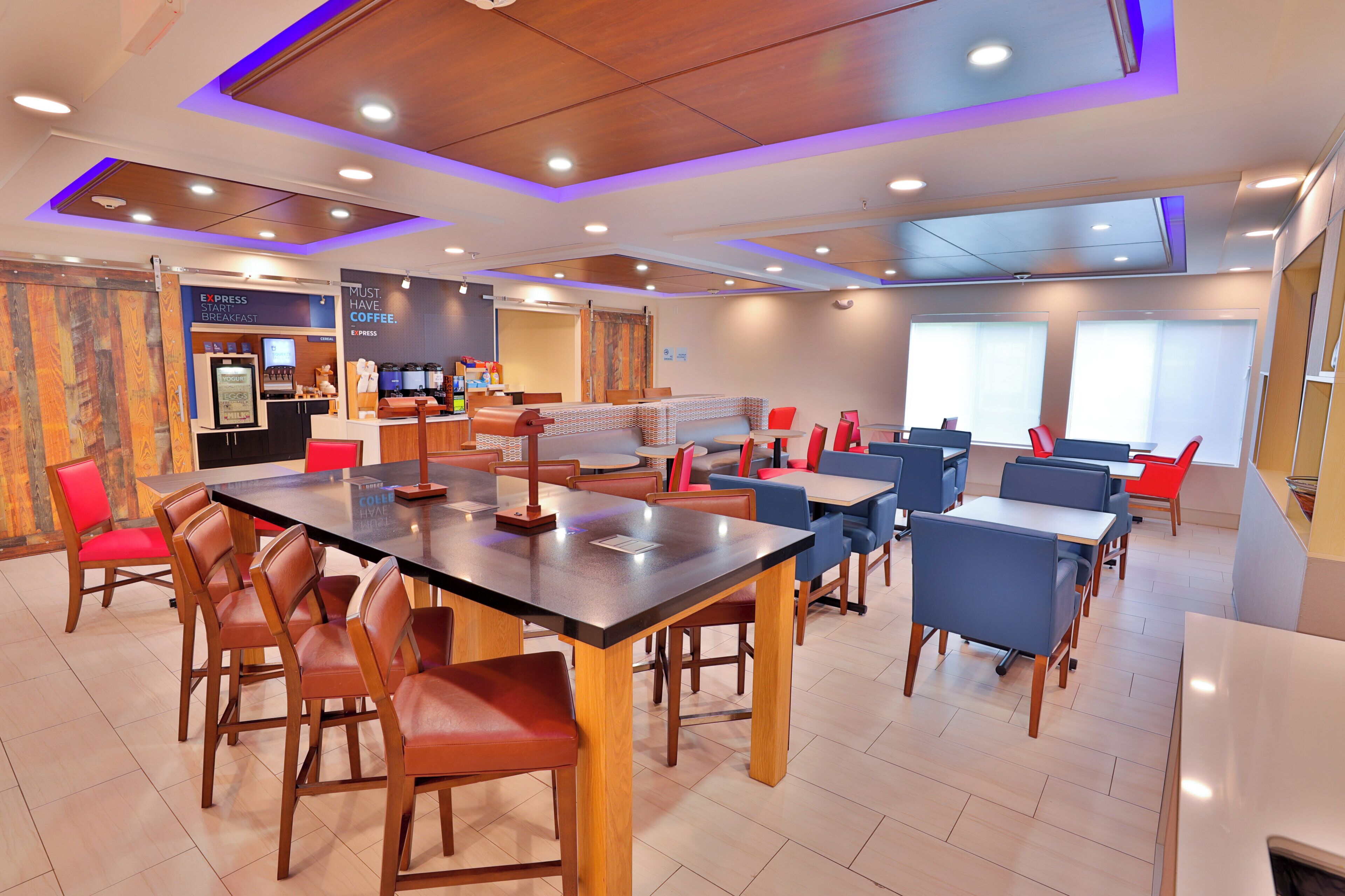 A modern dining area with a central table, surrounding booths, and a breakfast bar.