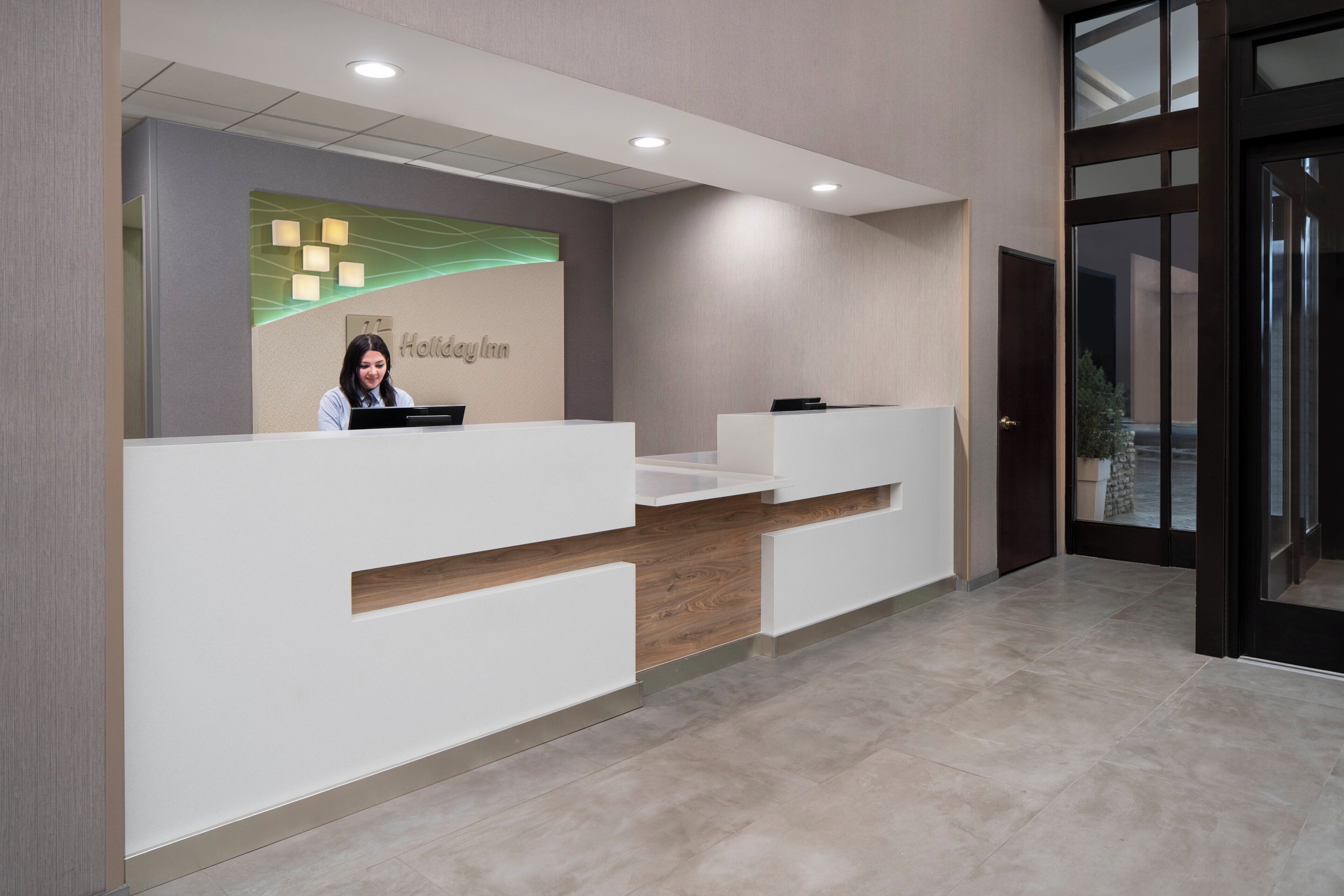 Un mostrador de recepción con un cartel que dice 'Holiday Inn' y un recepcionista.
