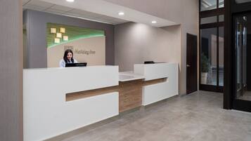 Un mostrador de recepción con un cartel que dice 'Holiday Inn' y un recepcionista.
