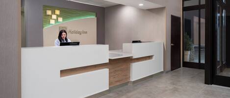 Un mostrador de recepción con un cartel que dice 'Holiday Inn' y un recepcionista.