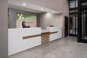 Een receptiebalie met een bord waarop 'Holiday Inn' staat en een receptionist.