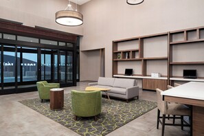 Een modern interieur met een bank, stoelen, een bureau en planken.