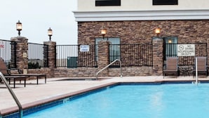 A swimming pool with lounge chairs and a sign indicating no lifeguard on duty.