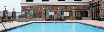 Una piscina con sillas de descanso y un cartel que indica que no hay socorrista de guardia.