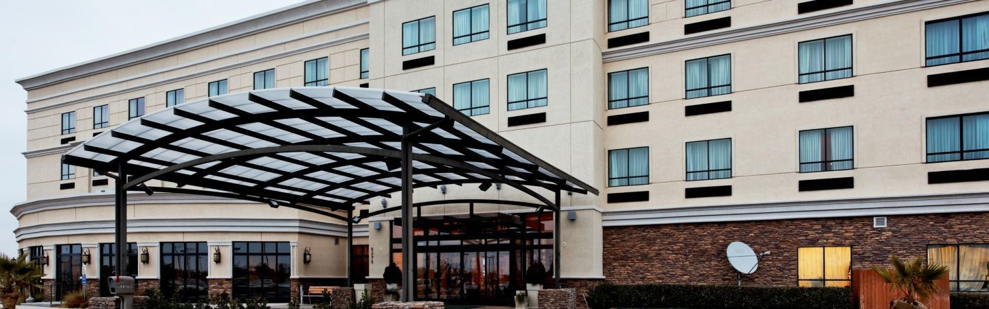 A hotel with a covered entrance, a stone facade, and multiple windows.