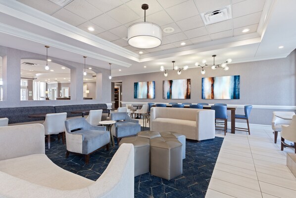 A spacious lobby with seating areas, a bar, and artwork on the walls.