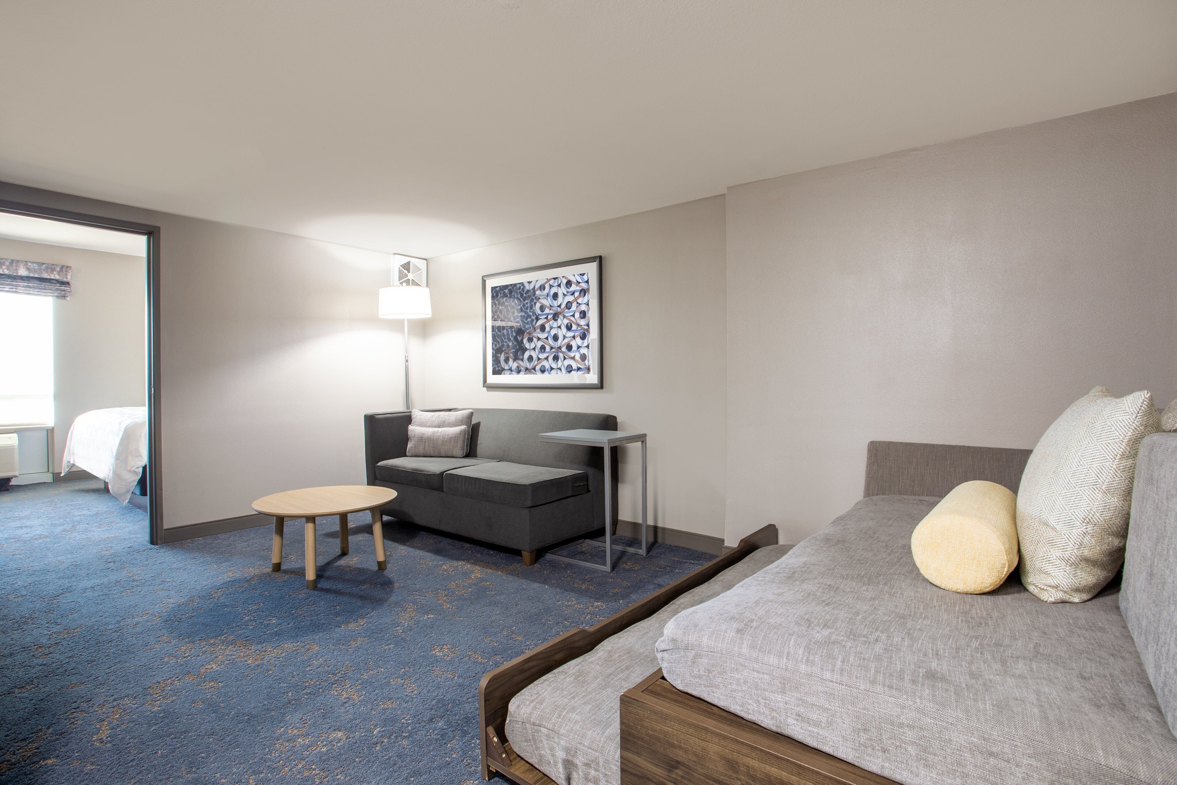 Ein Hotelzimmer mit Bett, Sofa, kleinem Tisch und Lampe.